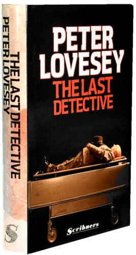 A book cover with a hospital gurney silhouetted on a black background; on top of the gurney lies a man in a suit and black shoes, a brown bowler hat resting on his chest. Above, white letters spell out “Peter Lovesey,” followed by red lettering that reads, “The Last Detective.” On the white spine of the book, thick black lettering reads, “The Last Detective” followed by “Peter Lovesey.”